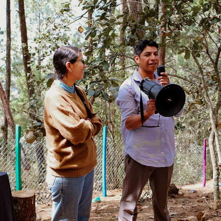 Integrantes de una comunidad conversan en el bosque mientras uno de ellos usa un megáfono
