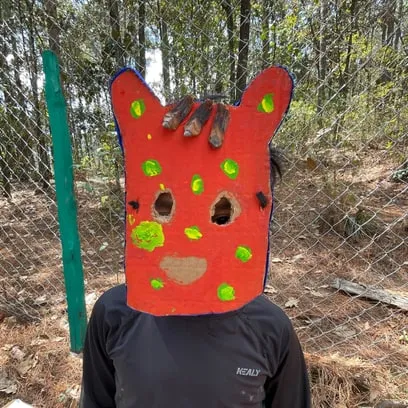Niño con una máscara artesanal de jaguar en el bosque