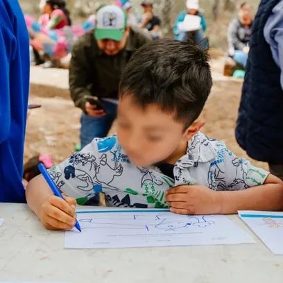 Niño dibuja sobre papel durante un taller comunitario