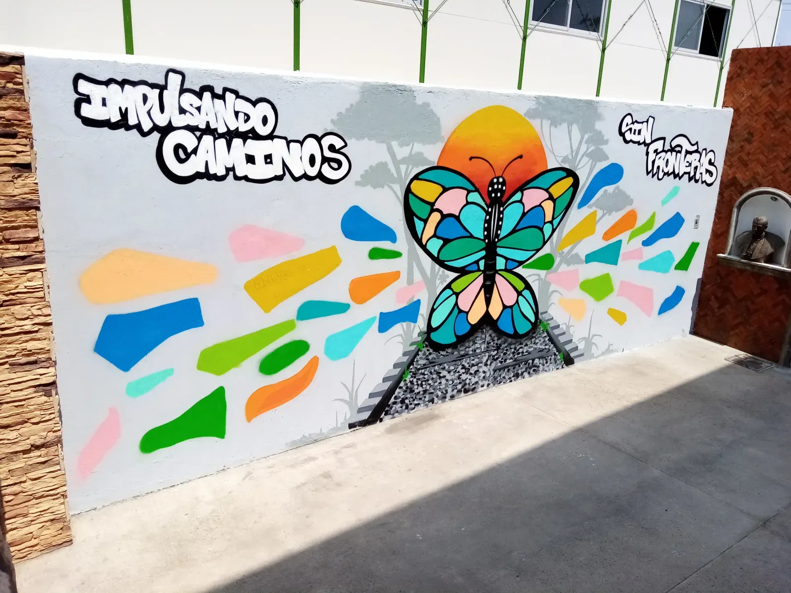 Mural colorido con una mariposa y el lema Impulsando Caminos en un muro exterior