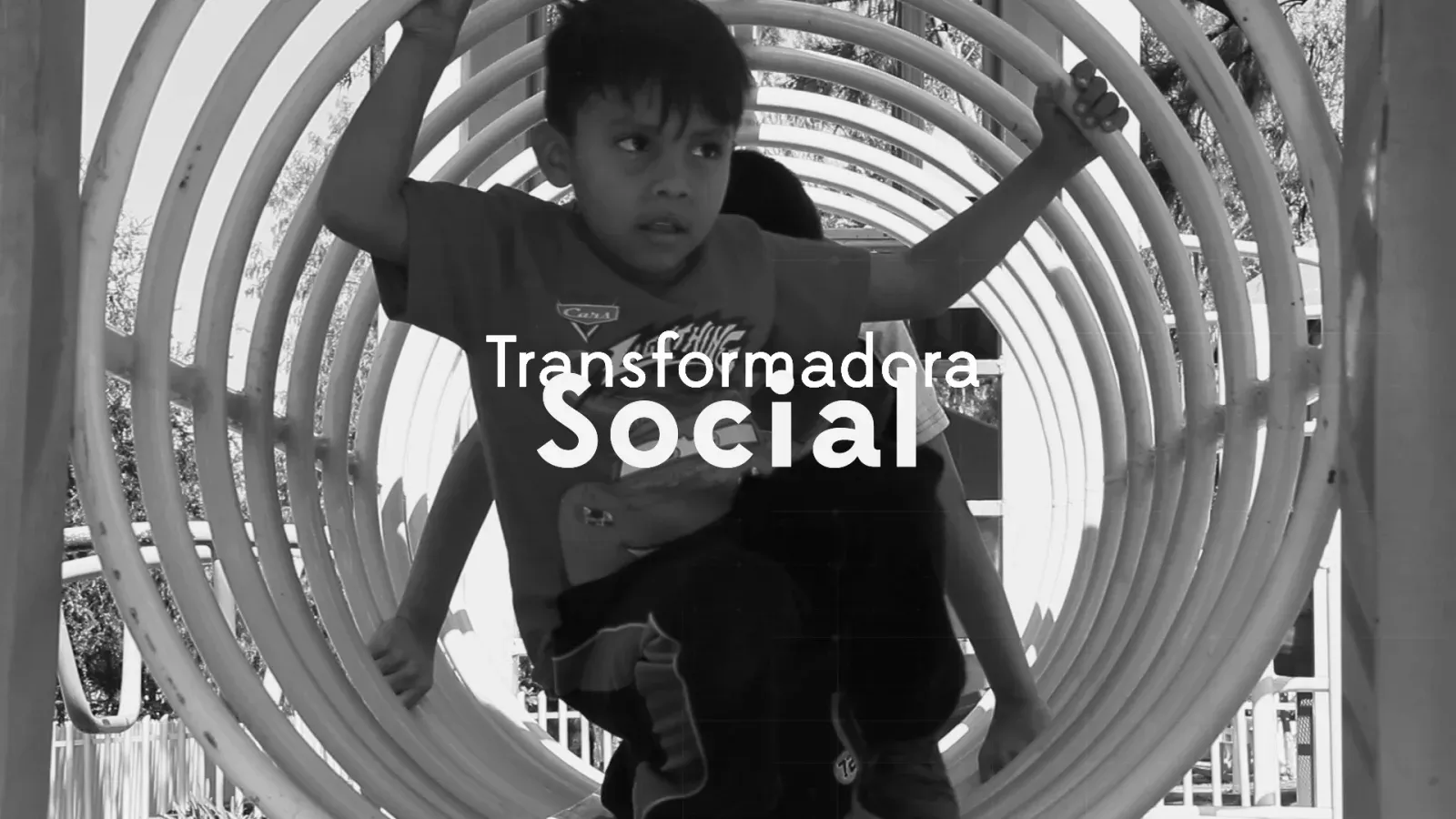 Niño trepa dentro de una estructura circular de juegos con el título Transformadora Social