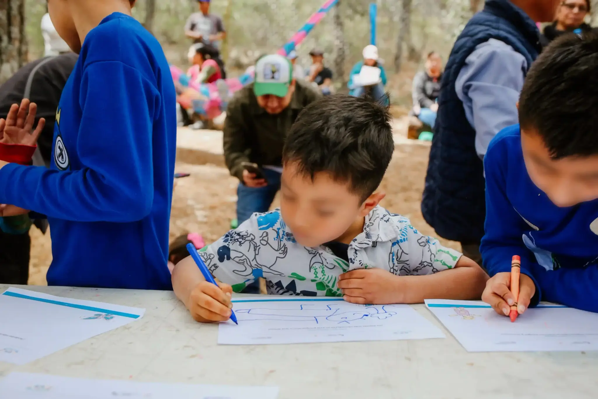 Niño dibuja con un crayón azul durante un taller participativo